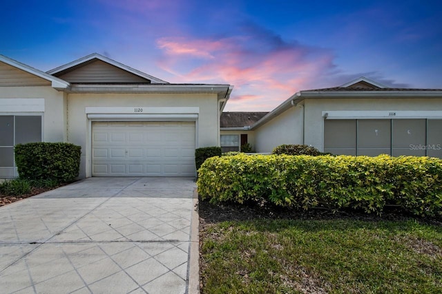 ranch-style house featuring stucco siding, an attached garage, and concrete driveway