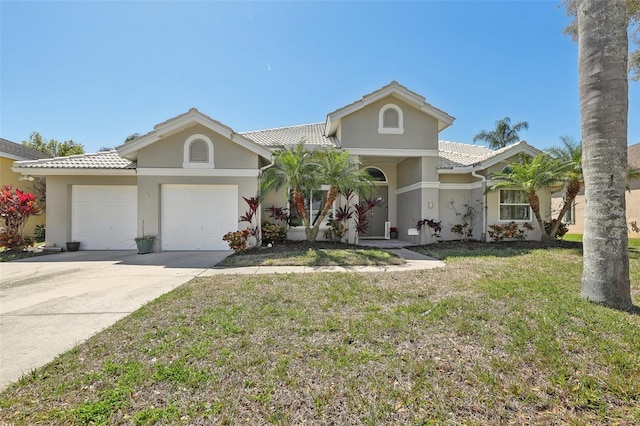 954 Cobblestone Ln, Tarpon Springs, FL 34688 - view of front of home featuring a front lawn, a garage, driveway, a tiled roof, and stucco siding