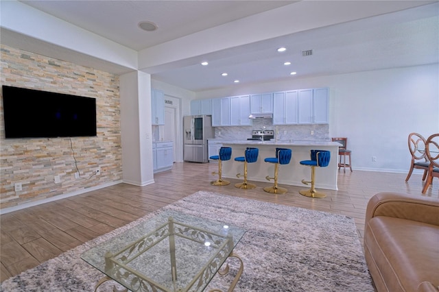 living room featuring baseboards, recessed lighting, visible vents, and light wood-style floors