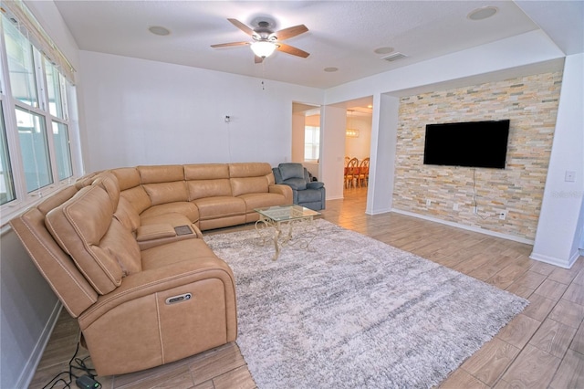 living area featuring a ceiling fan, wood finish floors, baseboards, and visible vents