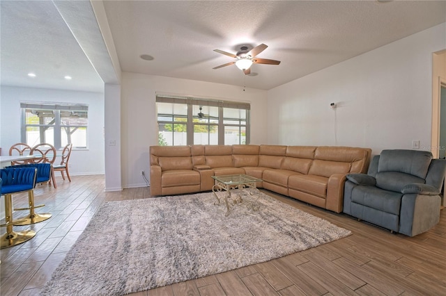 living room with wood finished floors, plenty of natural light, a textured ceiling, and ceiling fan