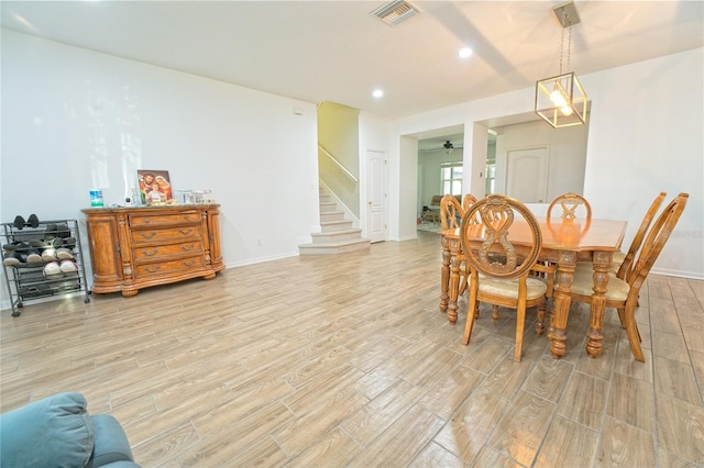 dining area featuring stairs, light wood-type flooring, baseboards, visible vents, and a ceiling fan