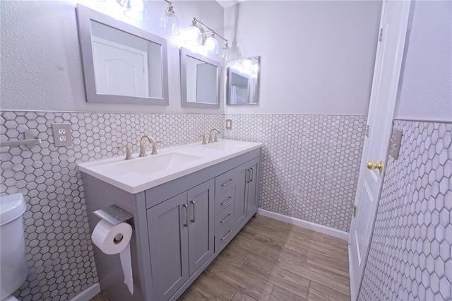 full bath with tile walls, double vanity, a sink, and wainscoting
