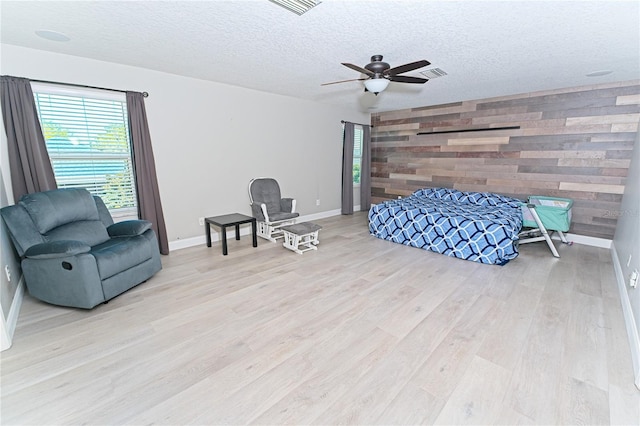 bedroom with wood finished floors, a textured ceiling, an accent wall, and visible vents