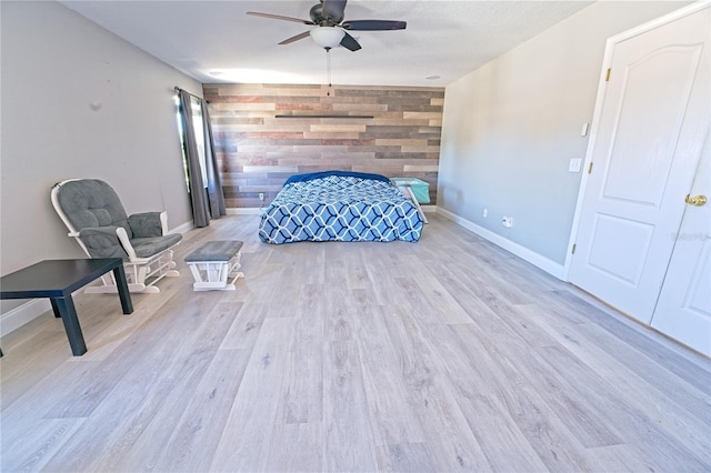 unfurnished bedroom featuring baseboards, wood walls, an accent wall, and wood finished floors