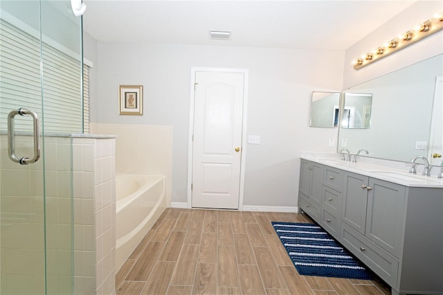 bathroom with wood finish floors, a sink, a garden tub, visible vents, and double vanity