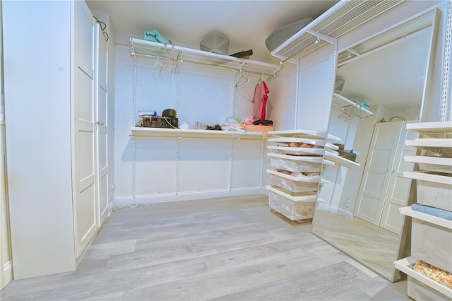 spacious closet with a wall mounted AC and light wood-style flooring