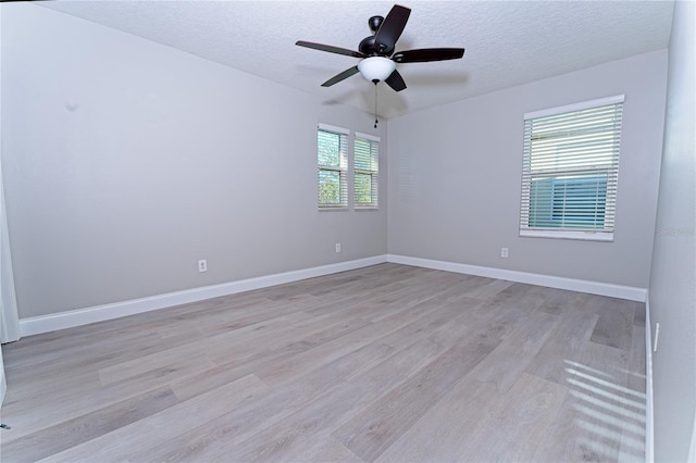 unfurnished room with a ceiling fan, baseboards, light wood finished floors, and a textured ceiling
