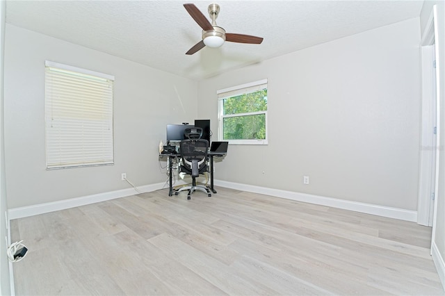 office area featuring baseboards, a textured ceiling, ceiling fan, and light wood-type flooring