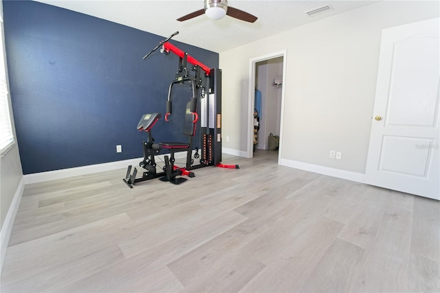 exercise area featuring wood finished floors, baseboards, ceiling fan, and visible vents