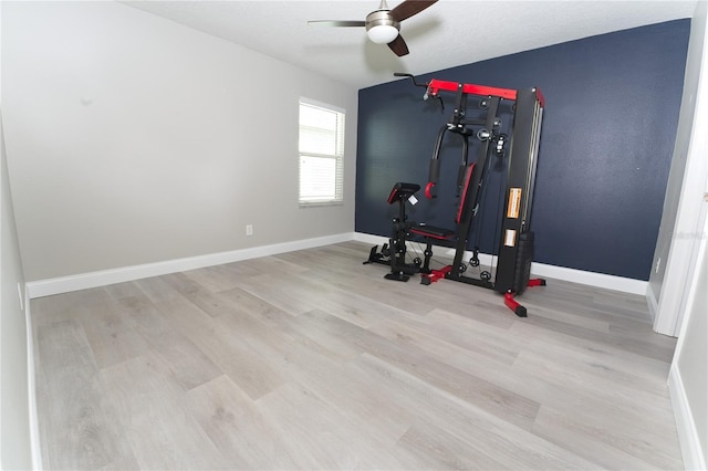 exercise area featuring wood finished floors, baseboards, and ceiling fan