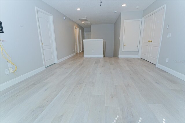 unfurnished living room with baseboards, light wood-type flooring, and recessed lighting