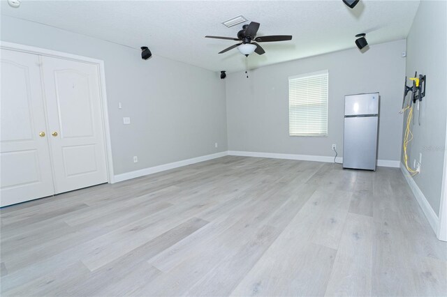 interior space featuring baseboards, visible vents, light wood-style flooring, and a ceiling fan