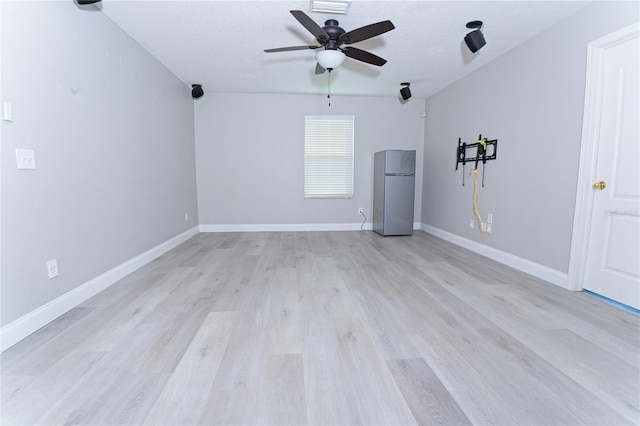 spare room featuring baseboards, ceiling fan, and light wood-style floors