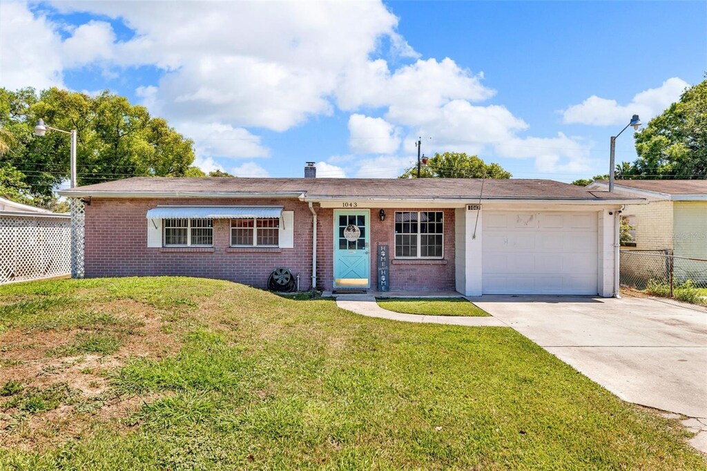 1043 Pineview Pl, Lakeland, FL 33801 - single story home featuring fence, driveway, a front lawn, a garage, and brick siding
