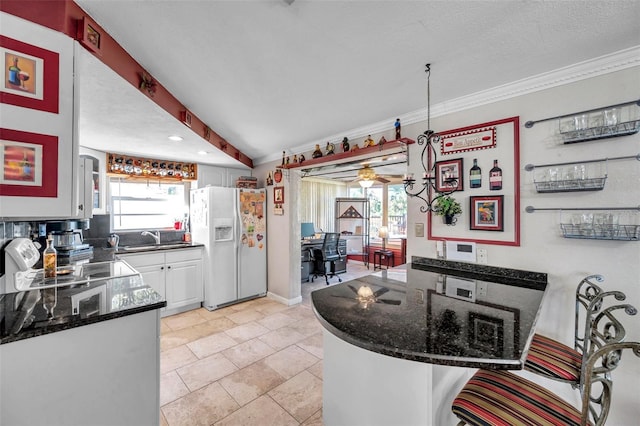 10035 Cherry Creek Ln, Port Richey, FL 34668 - kitchen featuring a ceiling fan, a peninsula, white refrigerator with ice dispenser, white cabinetry, and crown molding