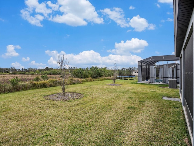 7494 Pool Compass Loop, Wesley Chapel, FL 33545 - view of grassy yard featuring central AC unit, a trampoline, and glass enclosure