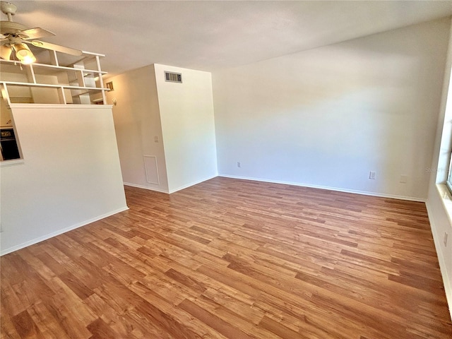 empty room featuring visible vents, baseboards, wood finished floors, and a ceiling fan