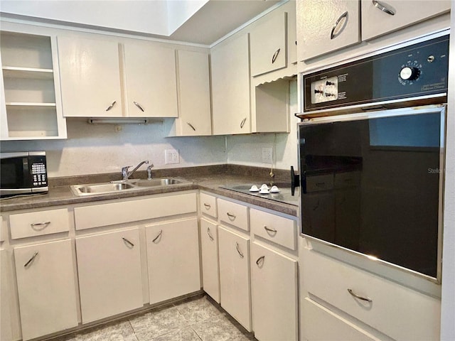 kitchen with dark countertops, stainless steel microwave, oven, light tile patterned floors, and a sink