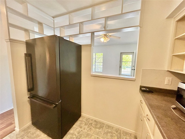kitchen with open shelves, a ceiling fan, baseboards, and freestanding refrigerator