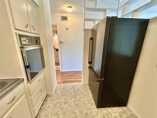 kitchen with white cabinetry, baseboards, visible vents, and stainless steel appliances