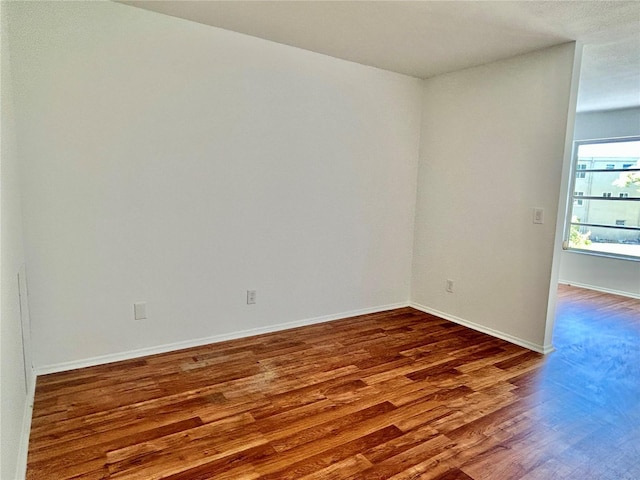 spare room featuring baseboards and wood finished floors