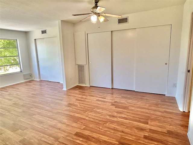 unfurnished bedroom with light wood-style flooring, a ceiling fan, and visible vents