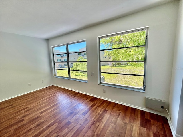 unfurnished room featuring a wealth of natural light, baseboards, and dark wood-style floors