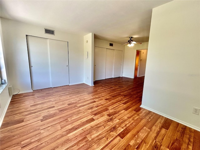 interior space with a ceiling fan, light wood-style floors, visible vents, and baseboards