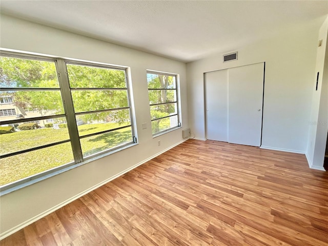 unfurnished bedroom featuring light wood-style flooring, baseboards, and visible vents