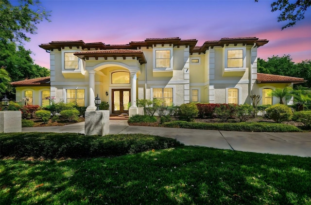 mediterranean / spanish-style house featuring a tiled roof, french doors, and stucco siding