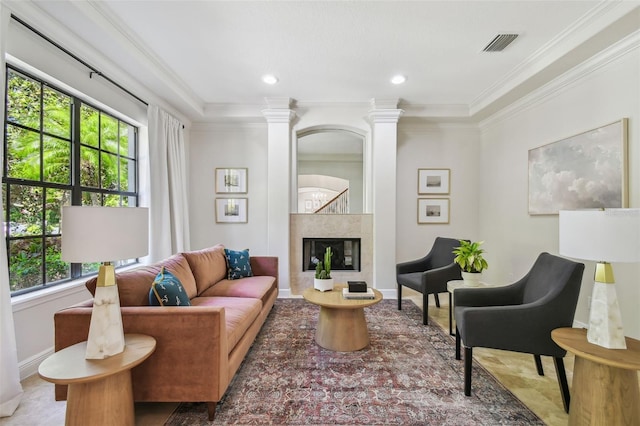 living room featuring ornate columns, visible vents, a premium fireplace, and ornamental molding