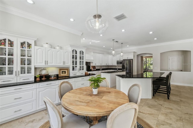 dining room with visible vents, crown molding, baseboards, recessed lighting, and arched walkways