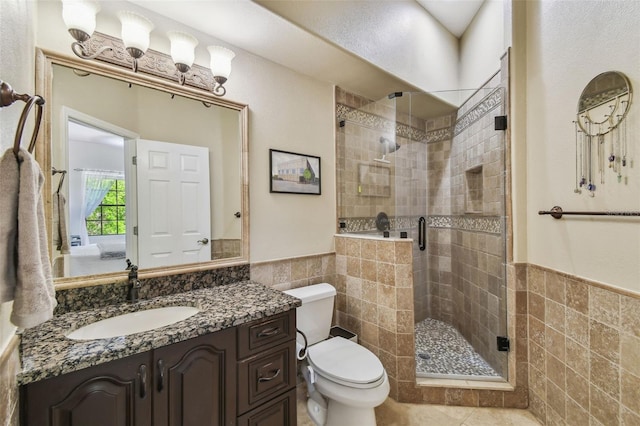 full bathroom featuring a wainscoted wall, toilet, tile walls, and a shower stall