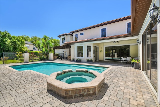 view of pool with a pool with connected hot tub, a patio, and fence