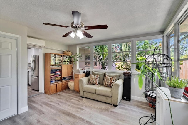 sunroom / solarium with a textured ceiling, wood finished floors, an AC wall unit, and baseboards