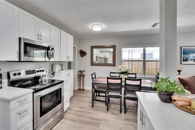 kitchen featuring white cabinetry, appliances with stainless steel finishes, visible vents, light stone countertops, and light wood finished floors