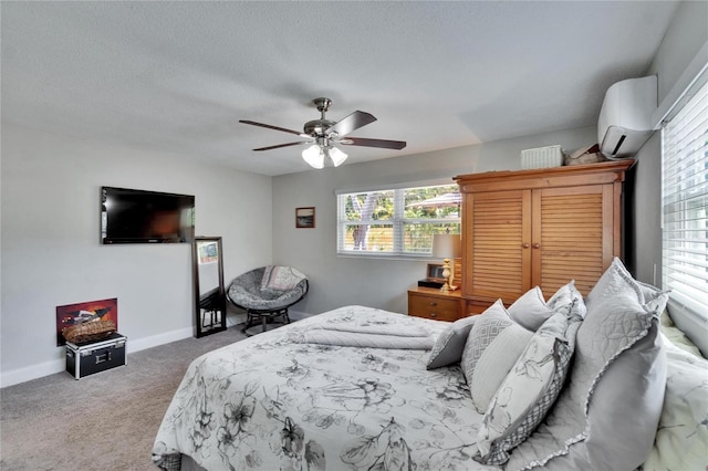 bedroom featuring carpet, an AC wall unit, baseboards, a ceiling fan, and a textured ceiling