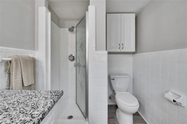 full bathroom with tile walls, wainscoting, and a stall shower
