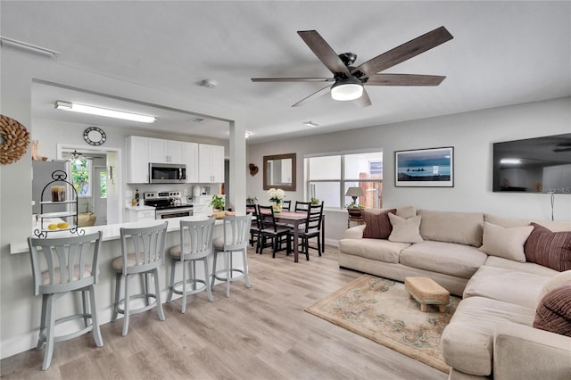 living room featuring a ceiling fan and light wood finished floors