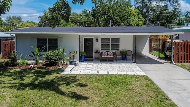 single story home with a front lawn, driveway, a carport, stucco siding, and fence
