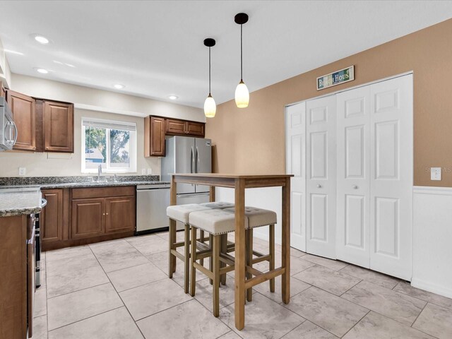 4500 23rd Ave S, Saint Petersburg, FL 33711 - kitchen with a sink, pendant lighting, stone countertops, brown cabinetry, and appliances with stainless steel finishes