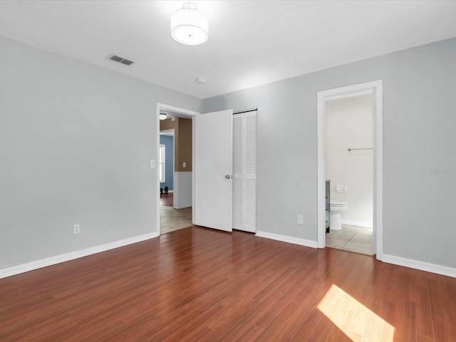 4500 23rd Ave S, Saint Petersburg, FL 33711 - unfurnished bedroom featuring ensuite bathroom, wood finished floors, a closet, baseboards, and visible vents