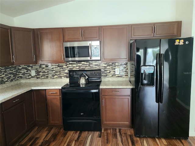 kitchen featuring dark wood-style flooring, tasteful backsplash, lofted ceiling, and black appliances
