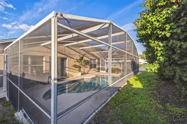 back of property with a patio area, glass enclosure, and an outdoor pool