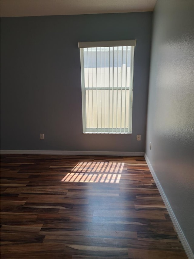empty room with dark wood finished floors and baseboards