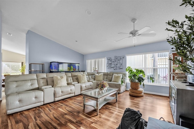 living area with lofted ceiling, ceiling fan, plenty of natural light, and wood finished floors