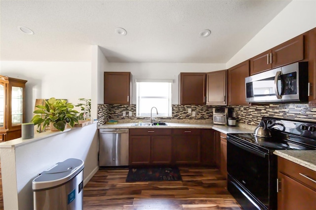 kitchen with a sink, a peninsula, stainless steel appliances, decorative backsplash, and light countertops