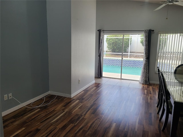 unfurnished room with baseboards, a ceiling fan, and dark wood-type flooring