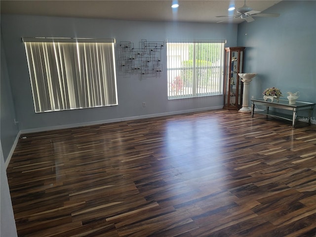empty room featuring baseboards, dark wood-style flooring, and ceiling fan